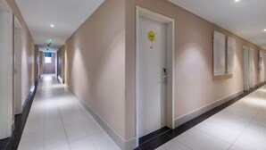 A long, narrow hotel corridor with beige walls, white doors, and a tiled floor. - 100 Inn (Shanghai Pudong Jinqiao) (Shanghai)