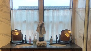 A wooden vanity with two sinks, a mirror, and a window above.