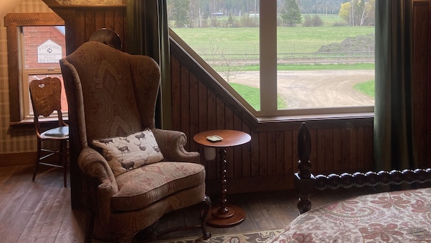 A cozy room with a large window, a wooden ceiling, and a patterned rug.