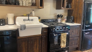 A kitchen with a white sink, black stove, and a black refrigerator.