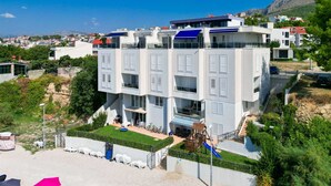 Un immeuble résidentiel à plusieurs étages, doté de balcons, d’un petit espace jardin et d’une aire de jeux.