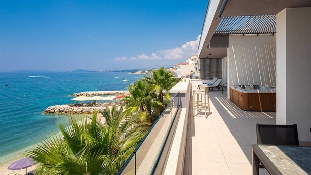 Ein Balkon mit Blick aufs Meer, einem Pool und einer Bar.