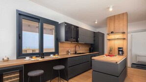 Eine moderne Küche mit dunklen Schränken, einer Holz Arbeitsplatte und einer integrierten Kochinsel mit Hockern.