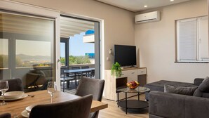 A modern living room with a dining area, a flat-screen TV, and a balcony with a view. - Villa Beverly Hills, Heated pool, Jacuzzi, 12 people (Zadar)