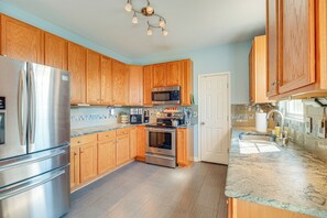 A kitchen with wooden cabinets, stainless steel appliances, and a granite countertop.