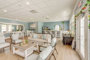 A spacious living area with a sofa, chairs, and a coffee table. There is a kitchen area with a refrigerator, stove, and bar stools. - Walk to Baypoint Resort & Lake! Extended Getaway (Marblehead)