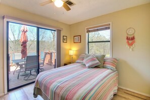 Un dormitorio con una cama, un ventanal, un atrapasueños y vistas a una terraza exterior.
