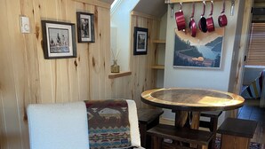Ein gemütliches Wohnzimmer mit einem hellen Sessel, einem Holztisch und einem gemusterten Teppich.