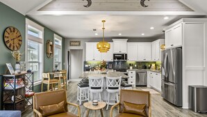 A spacious kitchen with white cabinets, stainless steel appliances, and a central island with seating. - Family Friendly-Sleeps 10-BBQ-EV-Game Rm-Walk to Beach-Fire Table-Fully Stocked (Crystal Beach)