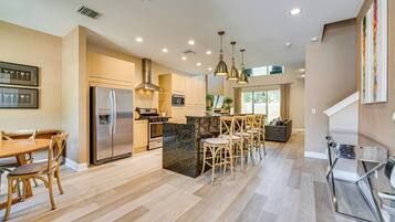 A modern kitchen with a central island, stainless steel appliances, and wooden chairs.