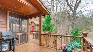 A wooden deck with a barbecue grill, outdoor seating, and potted plants. - 5 Mi to Cherokee Lake: Pet-Friendly Cabin w/ Deck! (Murphy)