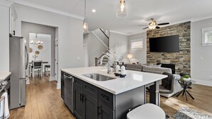 A modern kitchen with a central island, stainless steel appliances, and pendant lighting. - Elegant Atlanta Home with Fireplace & Private Yard (Atlanta)