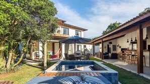 A backyard with a swimming pool, outdoor furniture, and a dining area. - Bz06 Casa com Piscina a 200M da praia (Buzios)