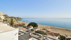 A coastal town with a beach, buildings, and a clear sky.