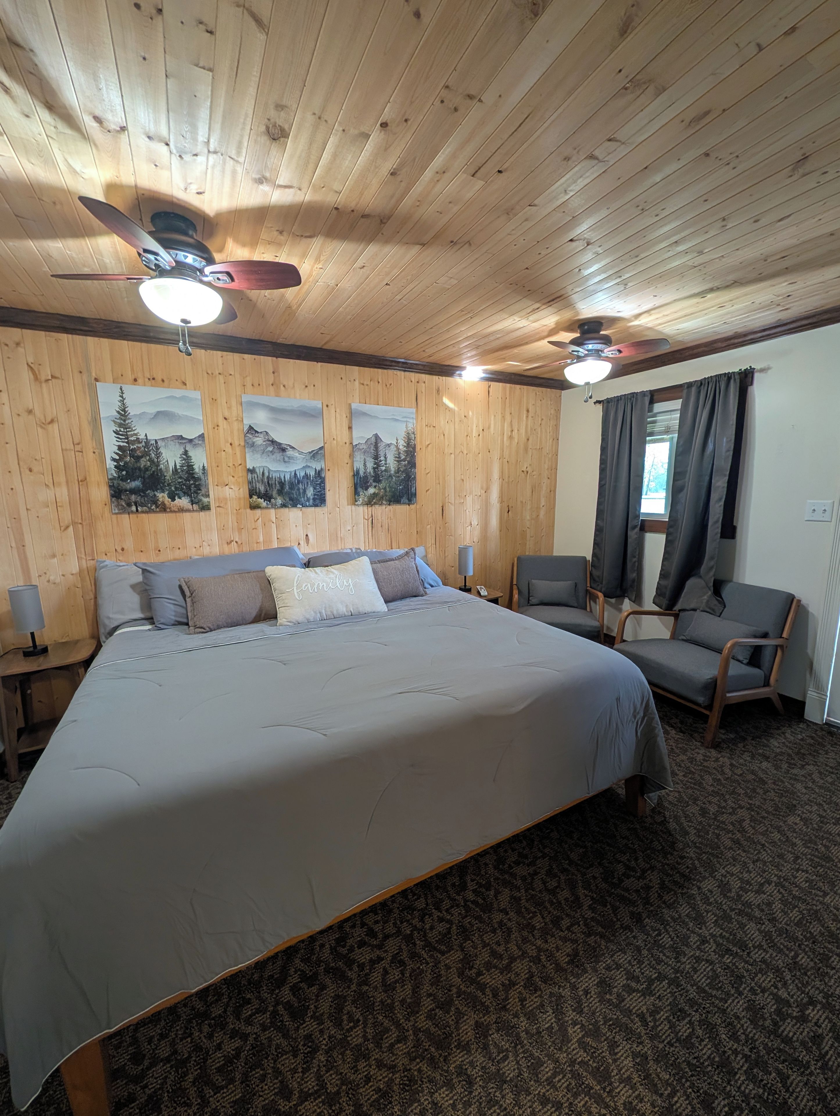 Ein Schlafzimmer mit einem großen Bett, zwei Stühlen, einem Deckenventilator und Wandbildern.