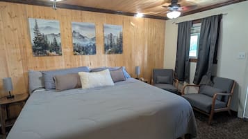Ein Schlafzimmer mit einem großen Bett, zwei Stühlen, einem Deckenventilator und Wandbildern.