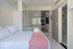 A modern hotel room with a neatly made bed, a pink towel, and a glass shower enclosure. - Lovely Just a few Minutes From Sugar Loaf F709 (Rio de Janeiro)