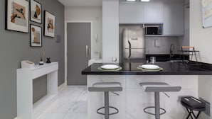A modern kitchen with a central island, bar stools, a microwave, and a refrigerator. - Lovely Just a few Minutes From Sugar Loaf F709 (Rio de Janeiro)