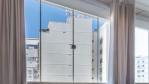 A modern room with two chairs, a large window with curtains, and a view of buildings outside. - Lovely Just a few Minutes From Sugar Loaf F709 (Rio de Janeiro)