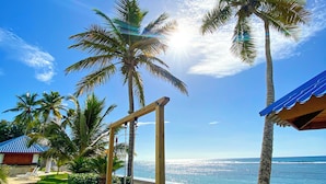 A tropical resort with palm trees, a beach view, and a clear sky. - Enjoy the Wonderful Ocean & Pool View from This 2BDR Apartment in Juan Dolio (Guayacanes)
