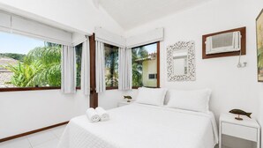 A hotel room with a bed, a nightstand, a mirror, and a window with curtains.