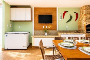 Eine moderne Küche mit integriertem Fernseher, einem Backofen aus Ziegeln und einer für vier Personen gedeckten Essecke.
