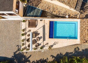 Eine Vogelperspektive eines Poolbereichs auf einem Dach mit einem rechteckigen Pool, Liegestühlen und einer Sitzecke mit Tisch und Stühlen.