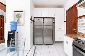 Cocina con armarios blancos, electrodomésticos de acero inoxidable y dispensador de agua.