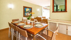 A dining area with a wooden table set for four, surrounded by wicker chairs.