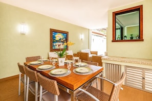 Un comedor con una mesa de madera dispuesta para cuatro personas, rodeada de sillas de mimbre.