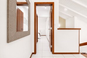 A hallway with a wooden door frame, a mirror, and a white tiled floor. - Bz08 Casa 200m da praia de Geribá (Buzios)