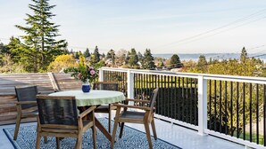 Une terrasse avec une table et des chaises, offrant une vue panoramique sur un paysage verdoyant, avec des arbres et une perspective lointaine.