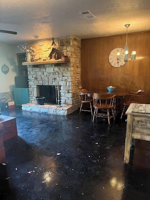 A rustic interior with a stone fireplace, wooden dining table, and chairs. - Cypress Grove Condo: Relax in Wimberley TX (Wimberley)