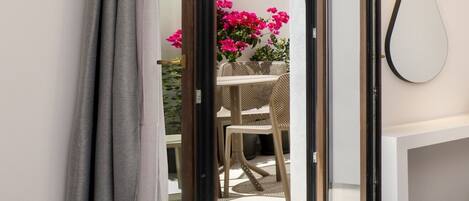 A room with a sliding glass door leading to an outdoor area with a table and chairs, a bench, and a hanging lamp.
