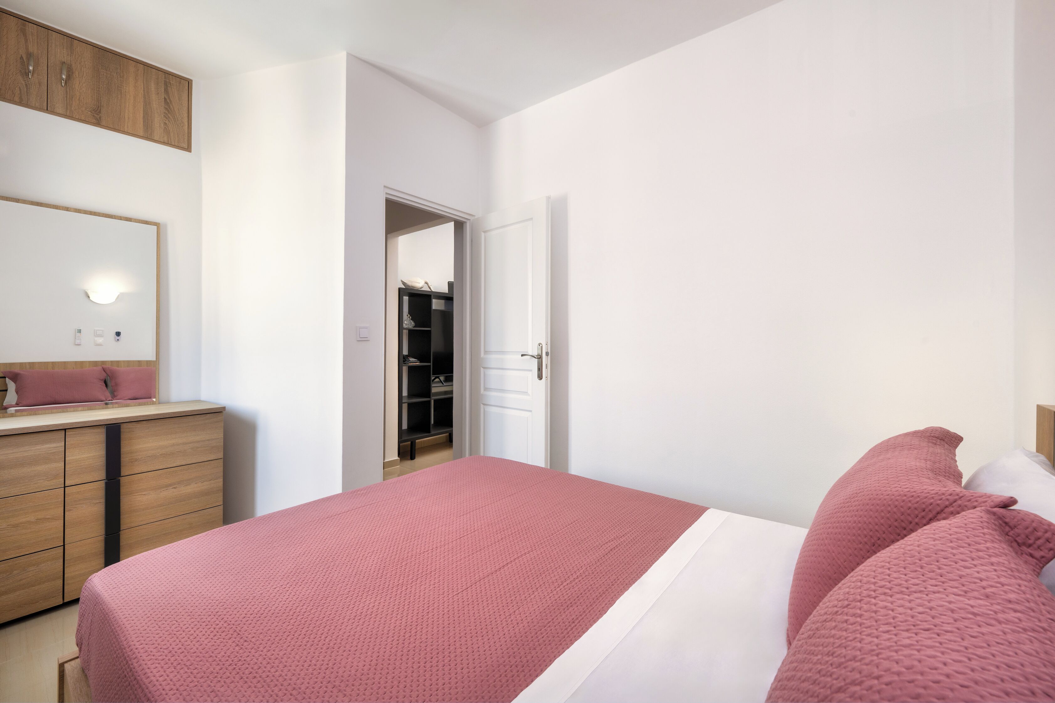 A bedroom with a bed, a dresser, a mirror, and a closet.