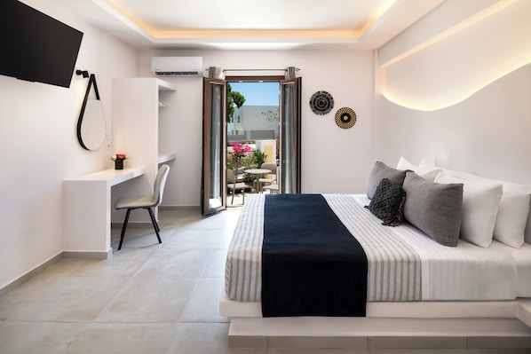 A modern bedroom with a bed, a desk, and a TV.