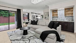 A modern living room with a sectional sofa, a round coffee table, and a chandelier. - Modern, remodeled, pool table in Wellington! (Wellington)