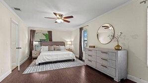 A bedroom with a bed, dresser, vanity, ceiling fan, and a window with curtains. - Modern, remodeled, pool table in Wellington! (Wellington)