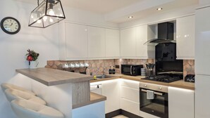 Una cocina moderna con armarios blancos, horno empotrado, microondas y estufa a gas.