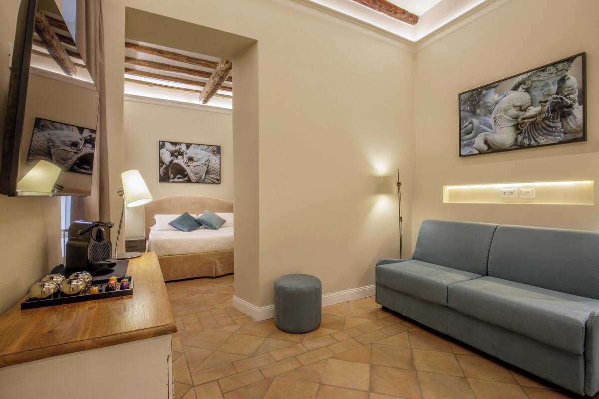 A modern hotel room with a bed, a sofa, a coffee table, and artwork on the walls.