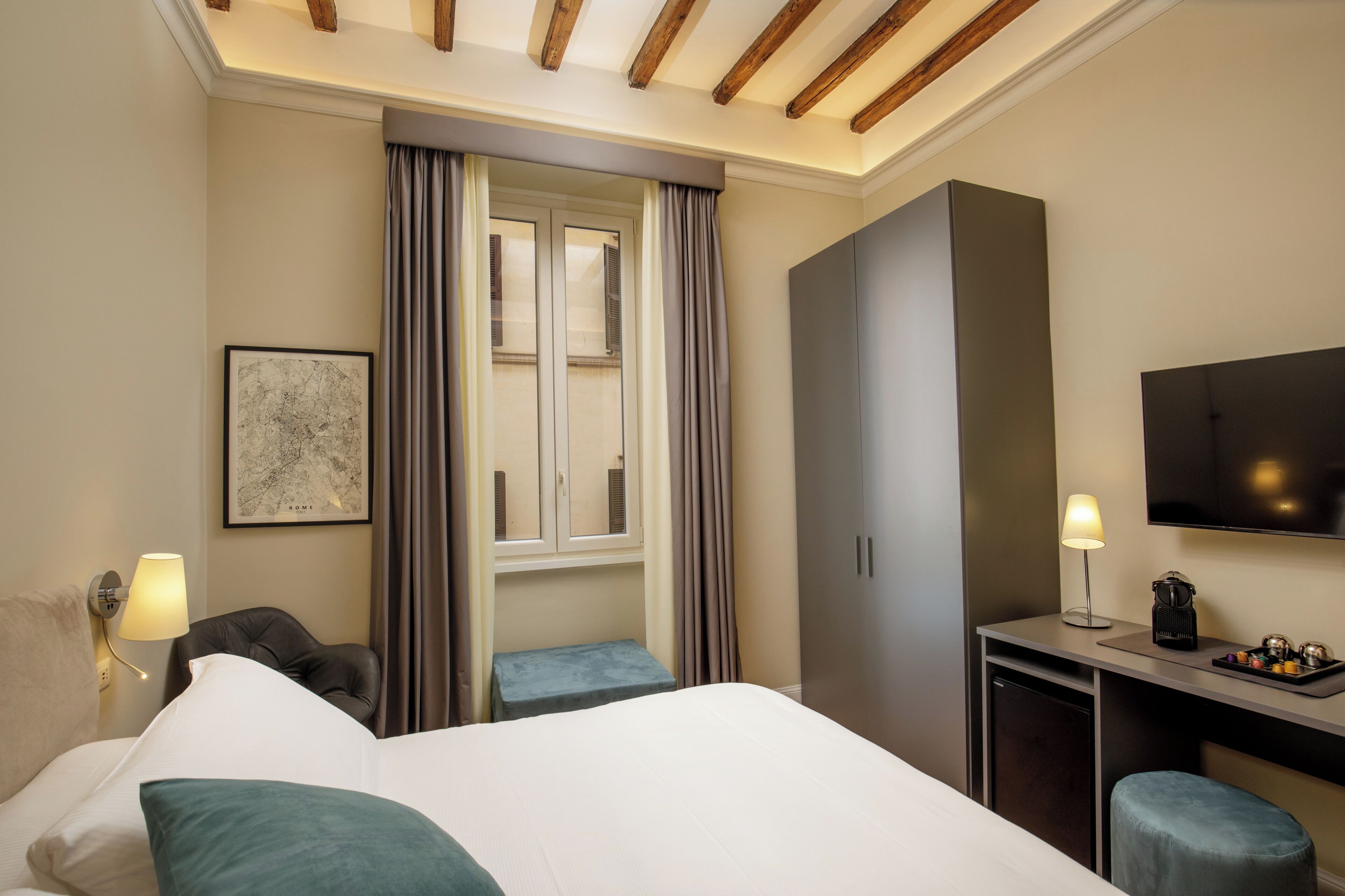 A hotel room with a bed, a desk, a chair, a TV, a lamp, and a window with curtains.
