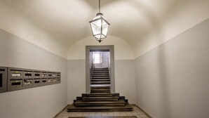 Un pasillo con piso de baldosas, una escalera y un candelabro.