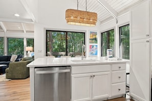 A modern kitchen with a large island, white cabinetry, and a hanging light fixture.