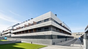 A modern multi-story building with a flat roof, large windows, and a central courtyard with a green lawn. - apartamento reformado con garaje de alquiler temporal (San Sebastián de los Reyes)