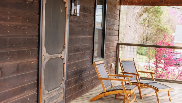 A wooden deck with two wooden chairs and a table. - Cute Little Cabin (Centerville)