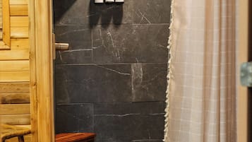 A shower area with a wooden door, a small stool, and a green rug.