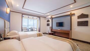 Habitación de hotel con dos camas, un escritorio, un televisor y una ventana con cortinas.