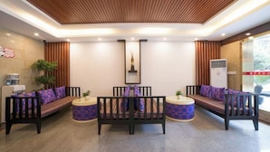 Uma área de recepção moderna com teto de madeira, balcão de atendimento e sofás e poltronas.