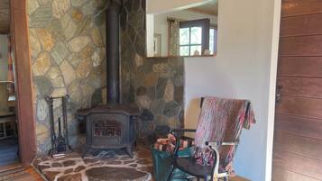 A stone fireplace with a chimney, a rocking chair, and a wooden door.