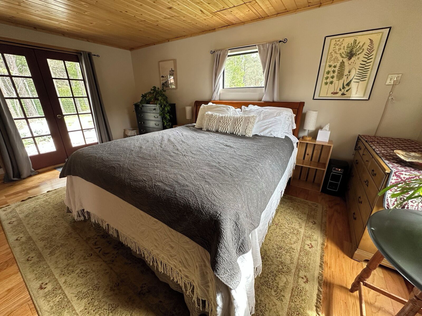 Un dormitorio con una cama grande, un aparador de madera, una silla y una ventana con cortinas.